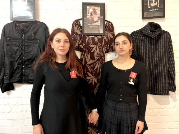 Daughters of slain protestor, Minoo Majidi standing next to her dress
