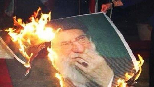 A burning banner of Iran’s ruler Ali Khamenei 