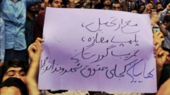 A protester holding a banner criticizing the persecution of Baha’i community in Iran