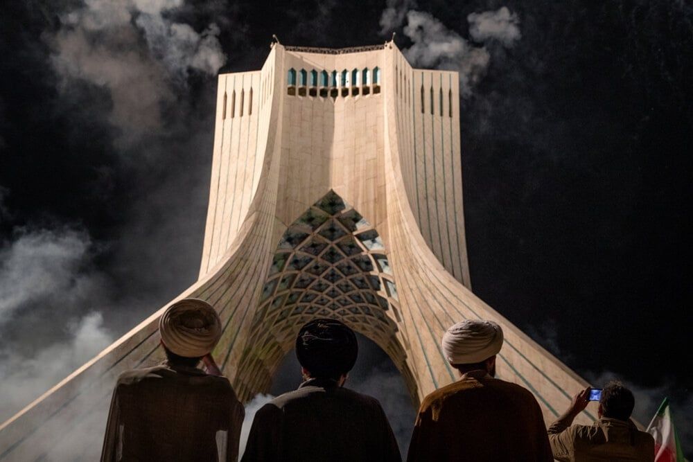 Three turbaned men watch fireworks over Tehran's iconic Azadi Tower in an event to mark the anniversary of the 1979 Revolution in Iran, February 10, 2026