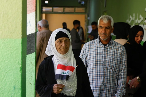 A woman holds an Iraqi flag at a polling station during a parliamentary election in Mosul, Iraq, November 11, 2025.
