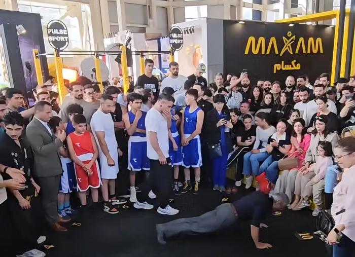 A man performs push-ups as spectators and young boxers watch during a fitness demonstration at the Fitex sports exhibition in Tehran, October 2026. (Social media)