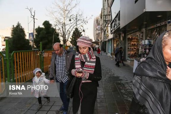 People looking at their cellphones on a street in Tehran (undated)