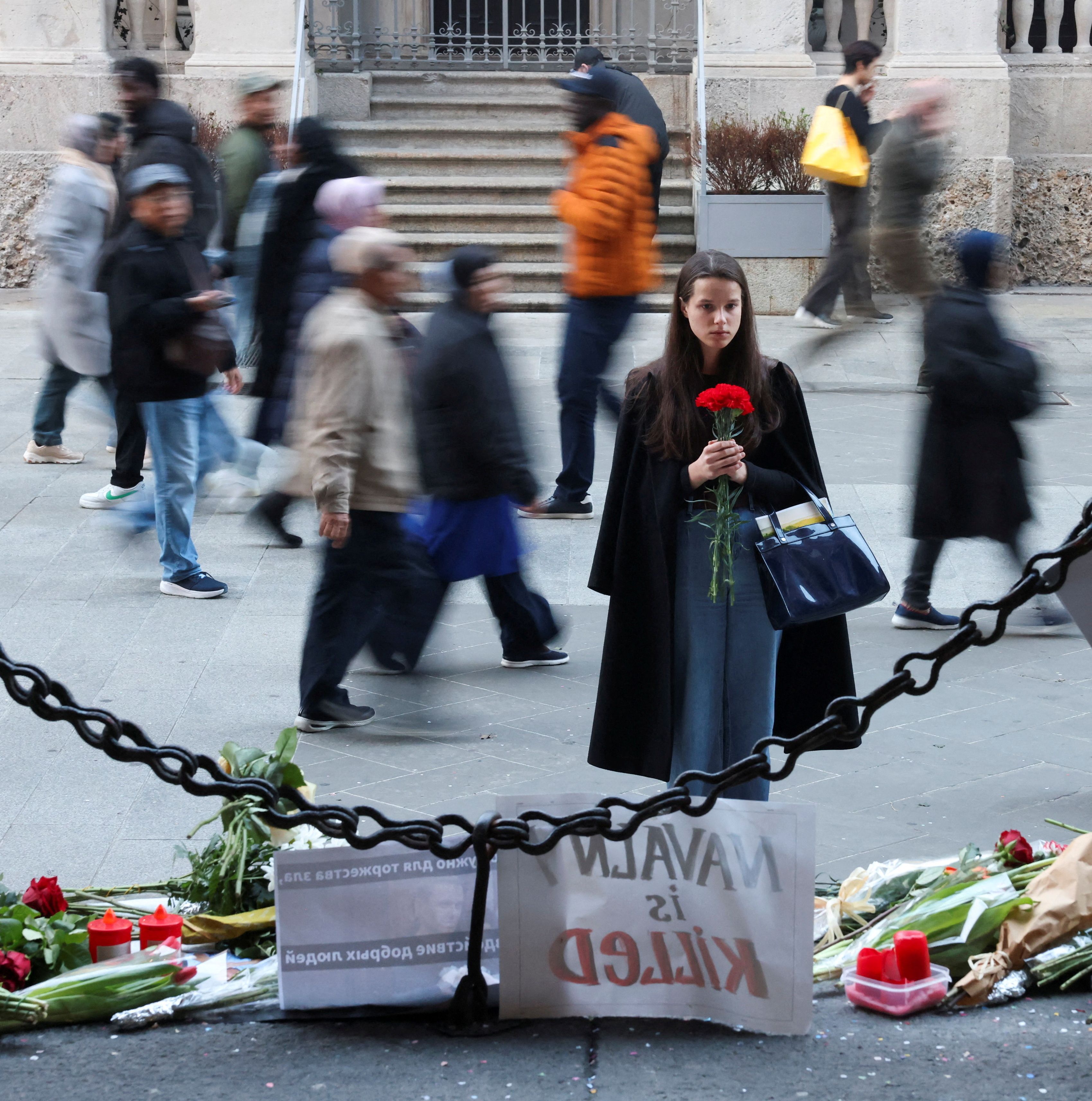 A woman holds flowers in front of a makeshift memorial to Russian opposition leader Alexei Navalny in Milan, Italy, February 19, 2024. 