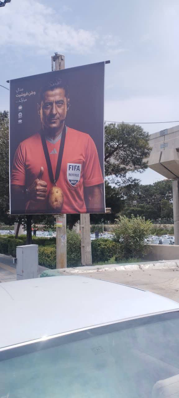 نصب بنر علیه فغانی در قم با کلیدواژه «وطن‌فروش» و تصویر سیب‌زمینی