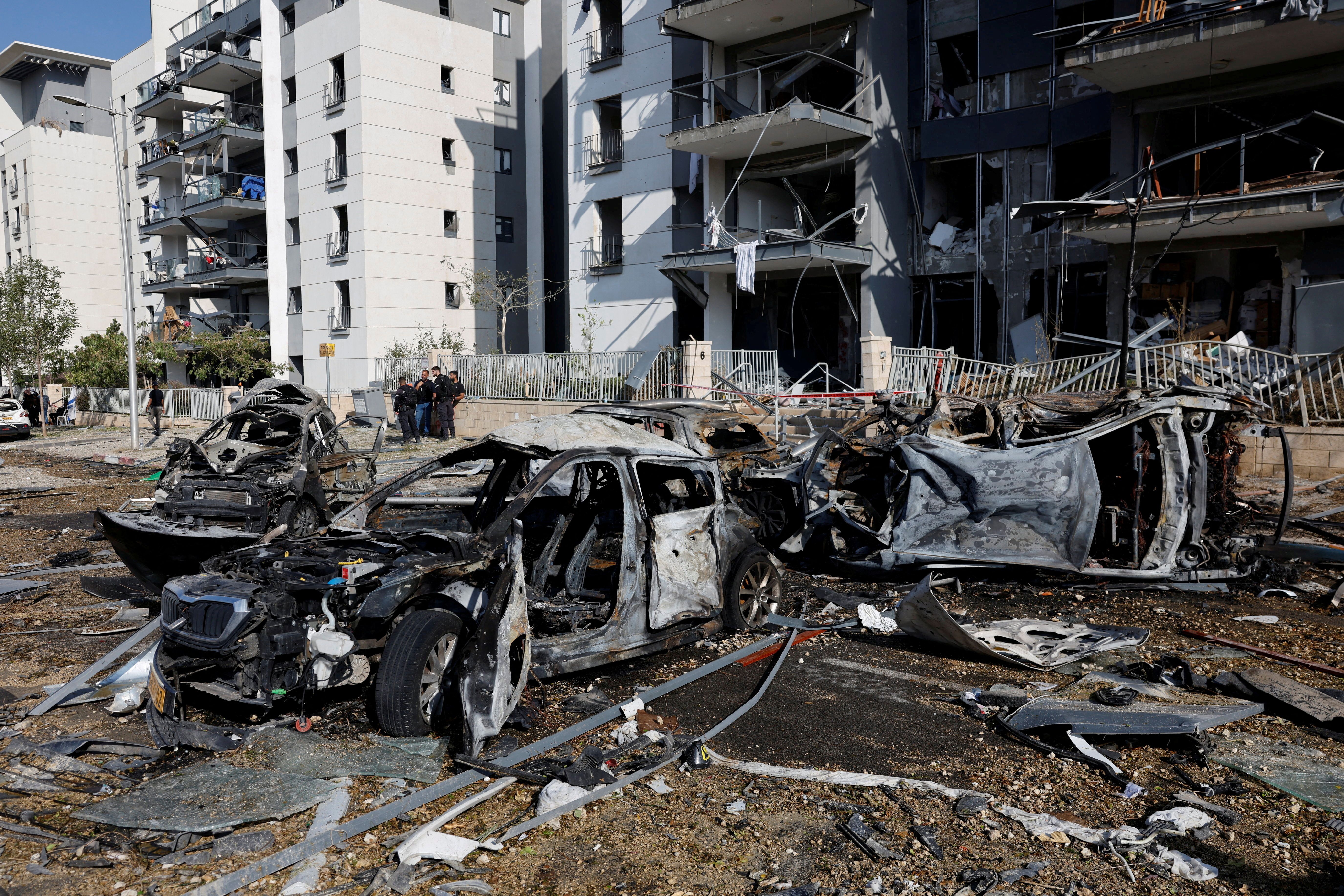 Emergency personnel work next to burnt cars and damaged residential buildings at an impact site following Iran's missile strike on Israel, in Be'er Sheva, Israel, June 20, 2025.