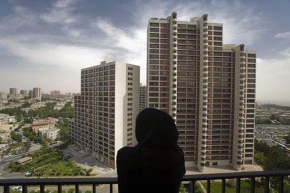A woman rests at her apartment's balcony in a residential building in northwestern Tehran