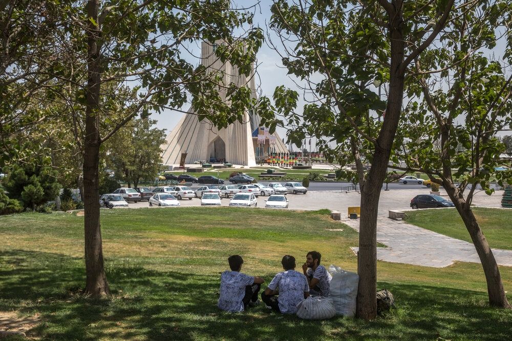 Three men sitting in the shade of a tree near Tehran's Azadi square, Iran, July 19, 2025