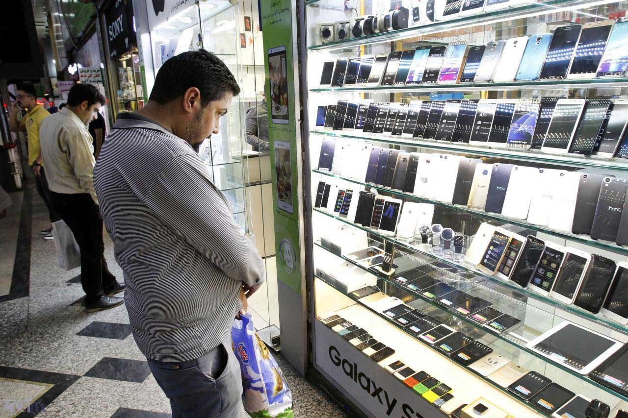 File photo of people looking at mobile phones and electronic devices displayed at a market in Iran.