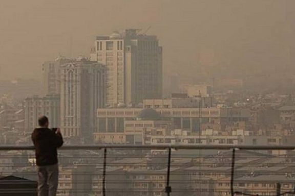 A man looks out over Tehran during heavy fog, December 2025