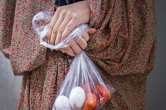 A woman clutches a small plastic bag containing a few eggs and tomatoes — an image of daily life amid soaring inflation in Iran.
