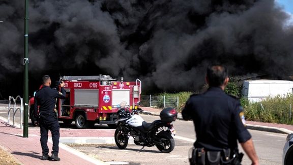 Israeli policemen stand next to smoke from a fire following incoming rockets from Lebanon to Israel in Bezet, northern Israel April 6, 2023