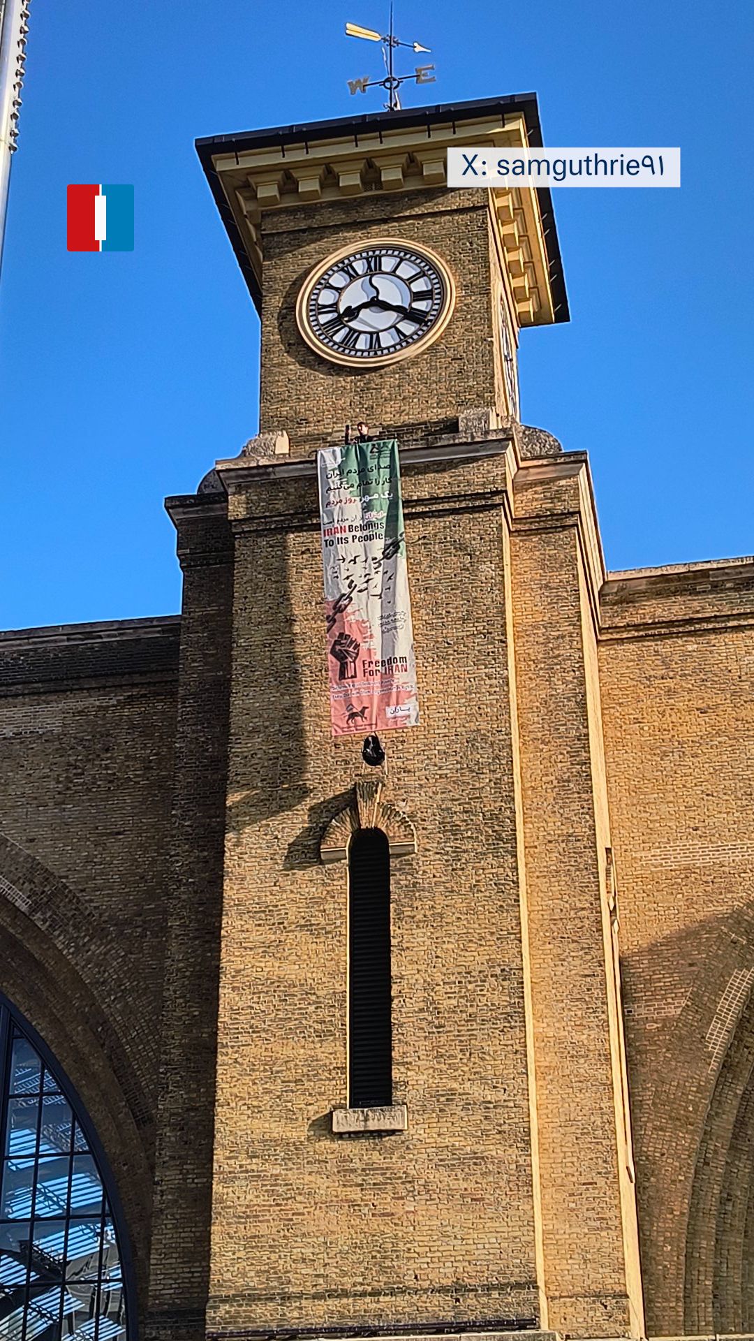 متظاهر يتسلق برج الساعة في محطة "كينغز كروس" بلندن رافعًا لافتة مناهضة للنظام الإيراني