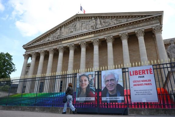 A woman walks past posters with the portraits of Cecile Kohler and Jacques Paris, two French citizens held in Iran, on the day of support rallies to mark their three-year detention and to demand their release, in front of the National Assembly in Paris, France, May 7, 2025.