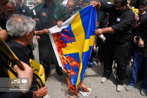 Iranians burning the flag of Sweden during a regime-sponsored rally in Tehran against the burning of the Quran (July 22, 2023)
