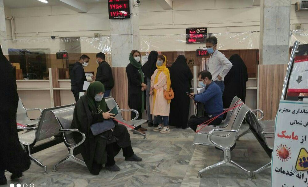 People stand in a line inside a bank  