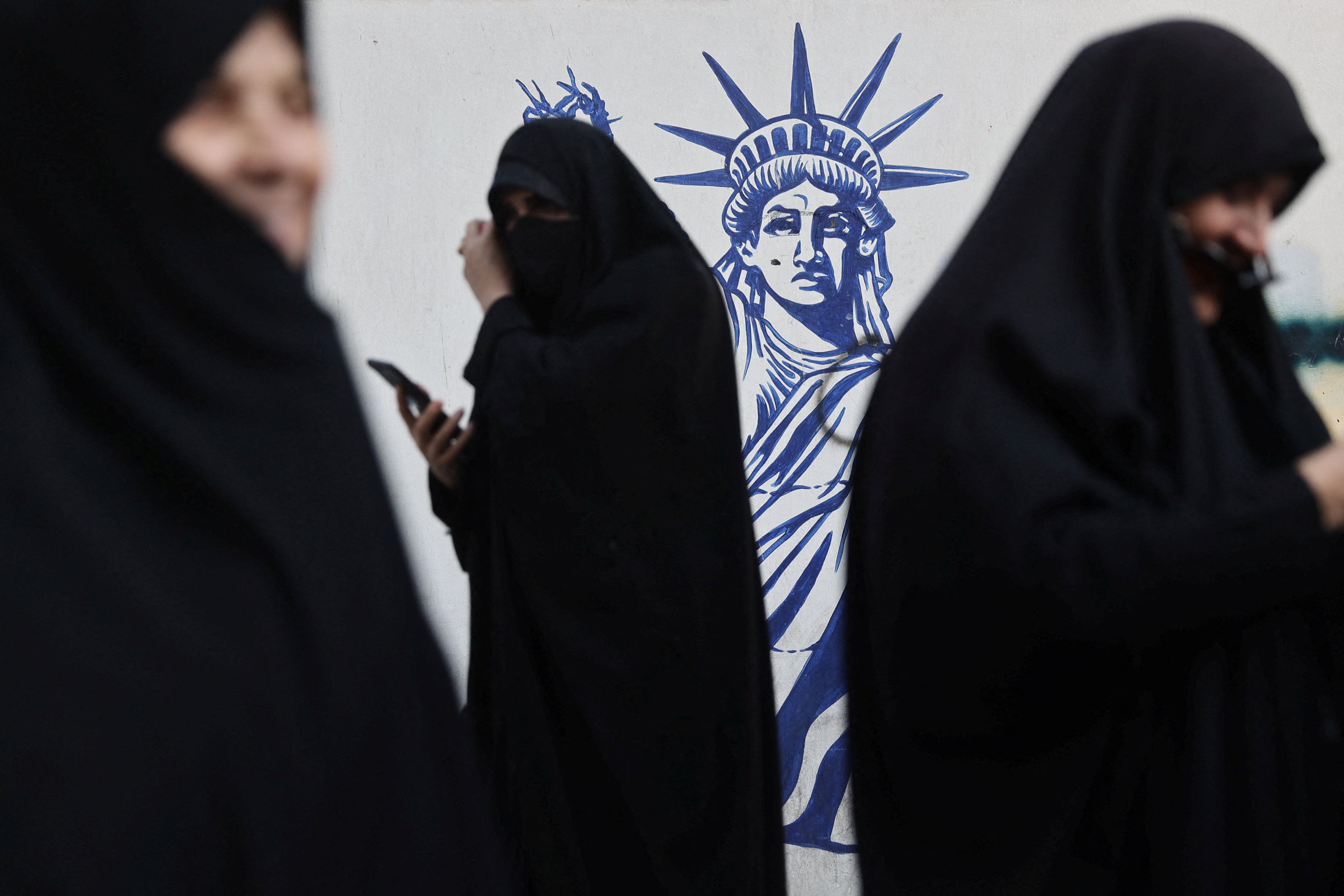 Women gather next to an anti-US mural, showing the Statue of Liberty with a severed arm, during the rallies in Tehran, November 4, 2025. 