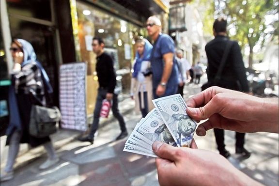 A man holding US dollar notes in a Tehran street outside a currency exchange. Undated