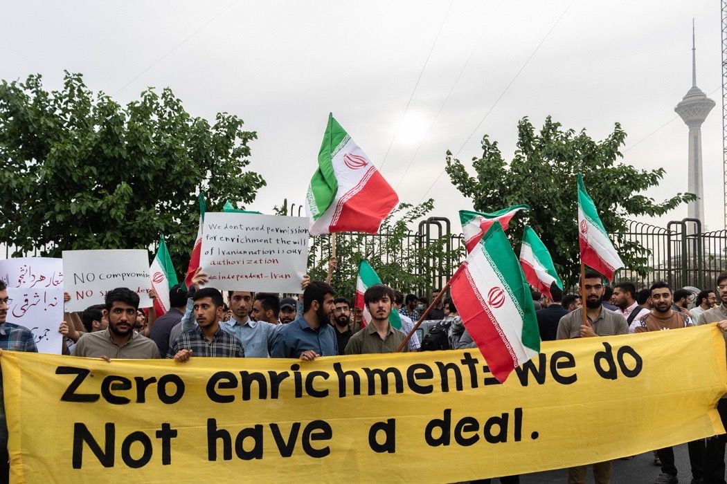 Demonstrators hold Iranian flags and a banner reading “Zero enrichment we do not have a deal” during a rally outside the Atomic Energy Organization of Iran in Tehran, May 2025