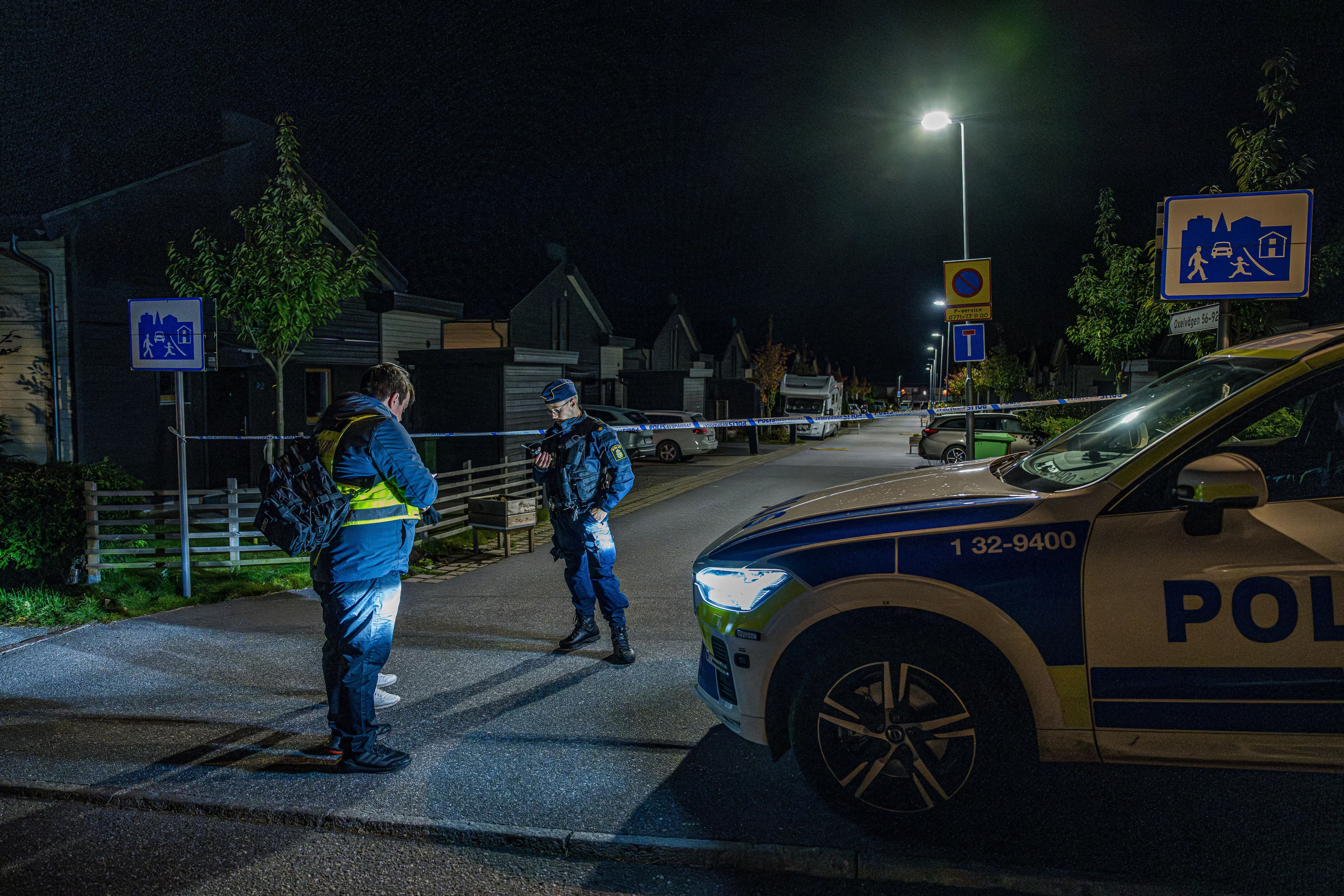 A police officer stands near police tape in Tullinge in Botkyrka, near Stockholm, Sweden (2023) 