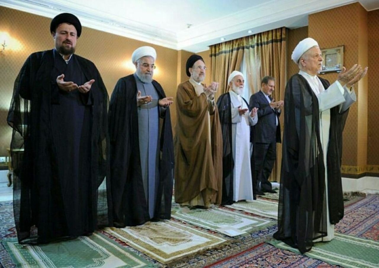 Former president Akbar Hashemi Rafsanjani leading a prayer with Ayatollah Ruhollah Khomeini's grandson Hassan Khomeini (left), former presidents Hassan Rouhani (2nd left) and Mohammad Khatami (center), former parliament speaker Ali Akbar Nateq-Nouri (2nd right) and former vice president Eshaq Jahangiri (right) standing behind him (undated)