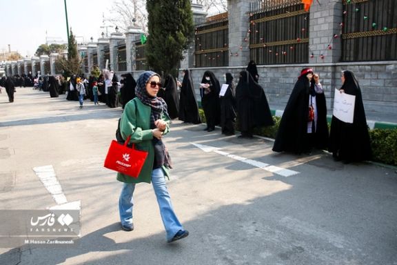 An Iranian woman walking in front of regime-sponsored pro-hijab protesters